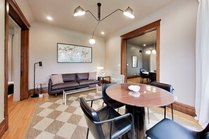A modern living room with a brown leather sofa, a round wooden table, and black chairs.