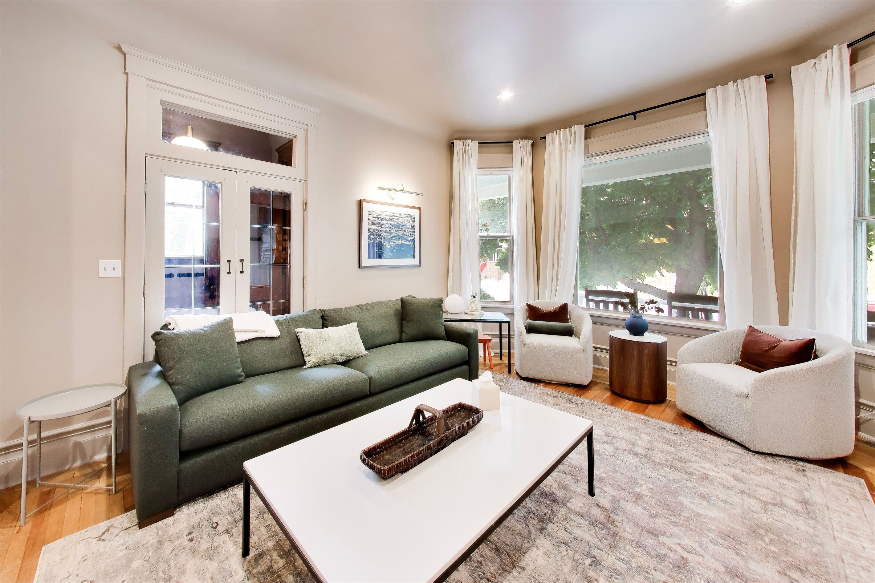 A living room with a green sofa, a white coffee table, and a white armchair.