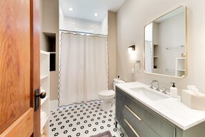 Un baño con inodoro, lavabo, espejo y cortina de ducha.