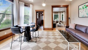 Een moderne woonkamer met een eethoek, grote ramen en een kaart aan de muur.