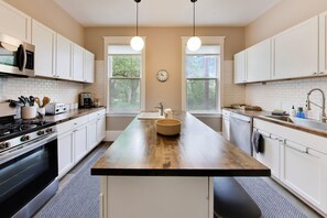 A modern kitchen with white cabinets, a central island, a stove, and a sink.