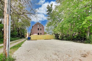 A gravel driveway leading to a brick building with a yellow fence in front.