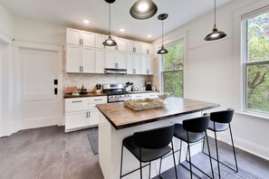 A modern kitchen with white cabinets, a central island with bar stools, and pendant lighting.