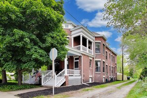A two-story brick building with a porch, a stop sign, and an American flag.