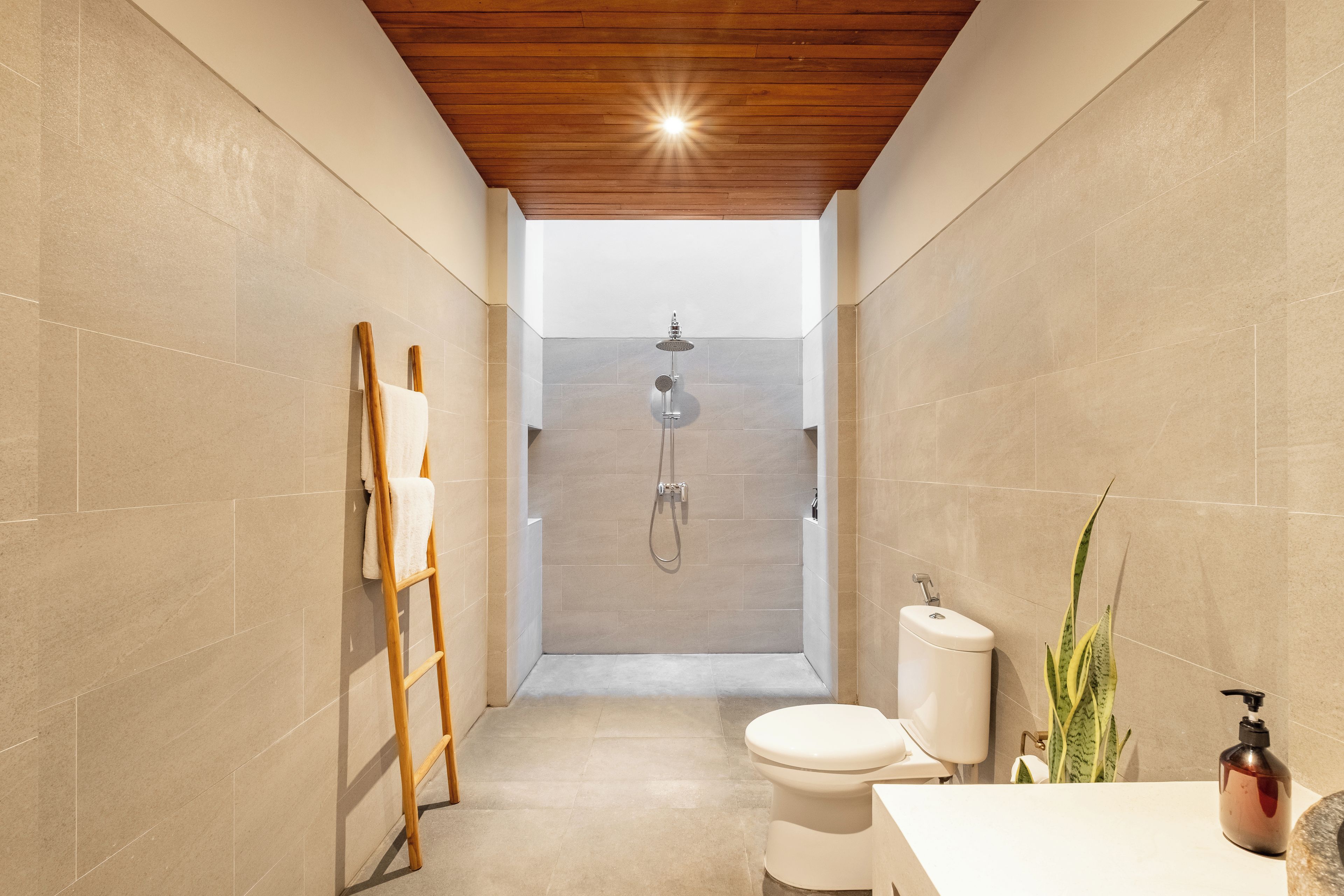 Un baño moderno con ducha, inodoro y una escalera de madera.