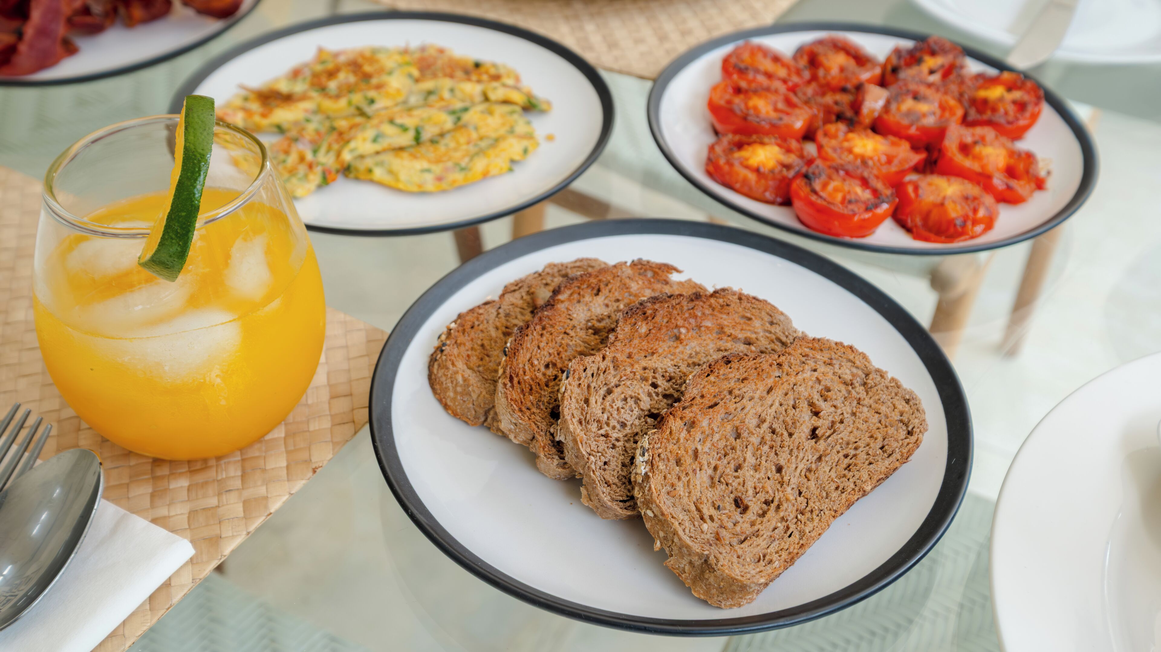 A breakfast setting with plates of toast, scrambled eggs, and roasted tomatoes.
