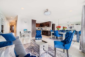 Ein modernes Wohnzimmer mit einer Couch, einem Glastisch und blauen Stühlen.