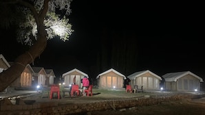 Una fila di piccole cabine a forma di tenda, con un muro di pietra in primo piano.