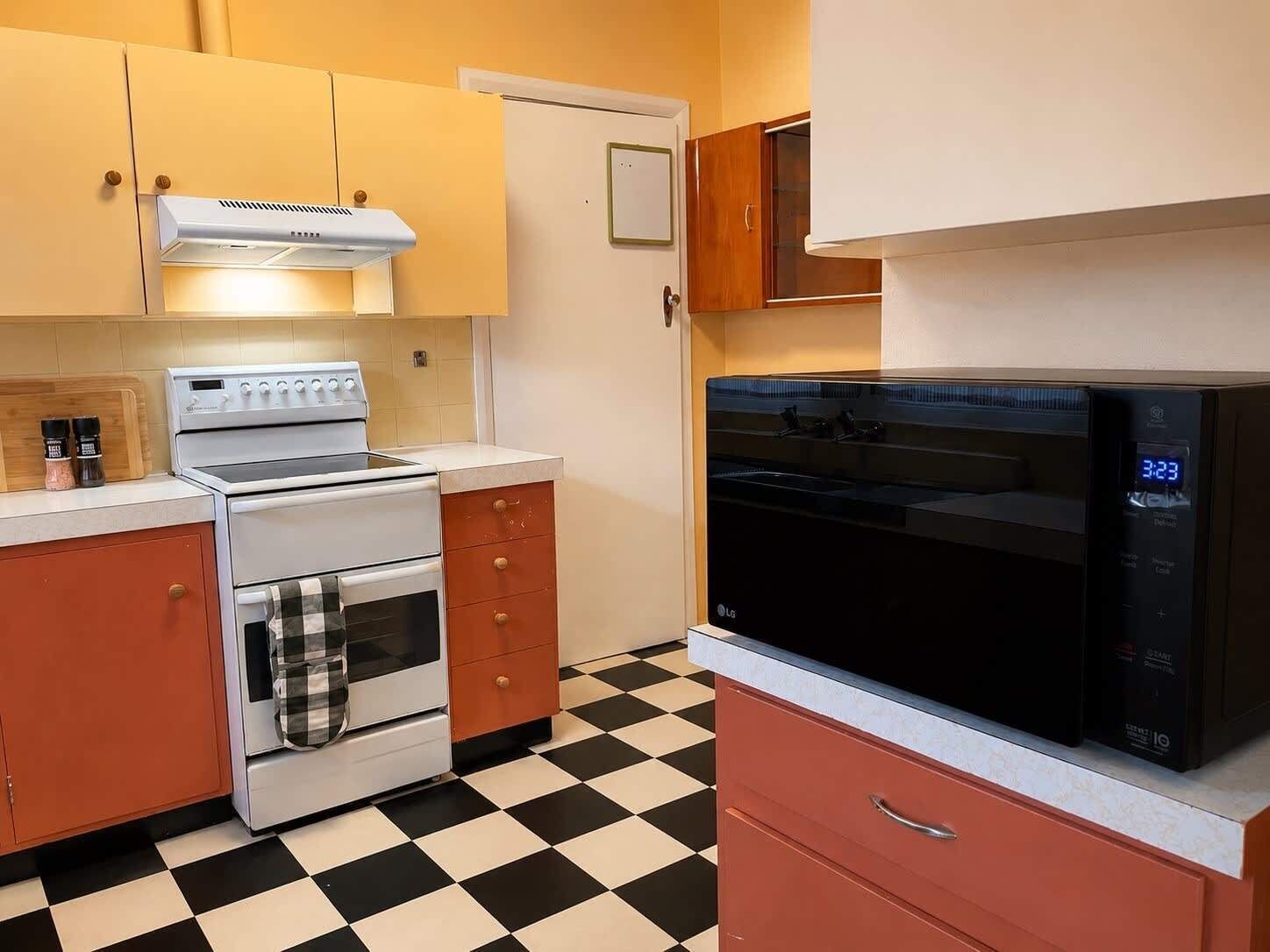 Une cuisine équipée d’une cuisinière, d’un four, d’un four à micro-ondes et dotée d’un sol à carreaux.