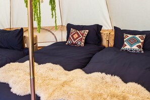 A tent with two beds, each with a pillow and a fluffy rug.
