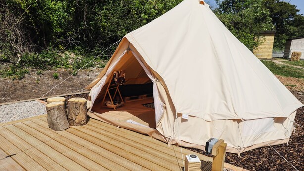 A tent with a wooden deck, a small table, and a chair.