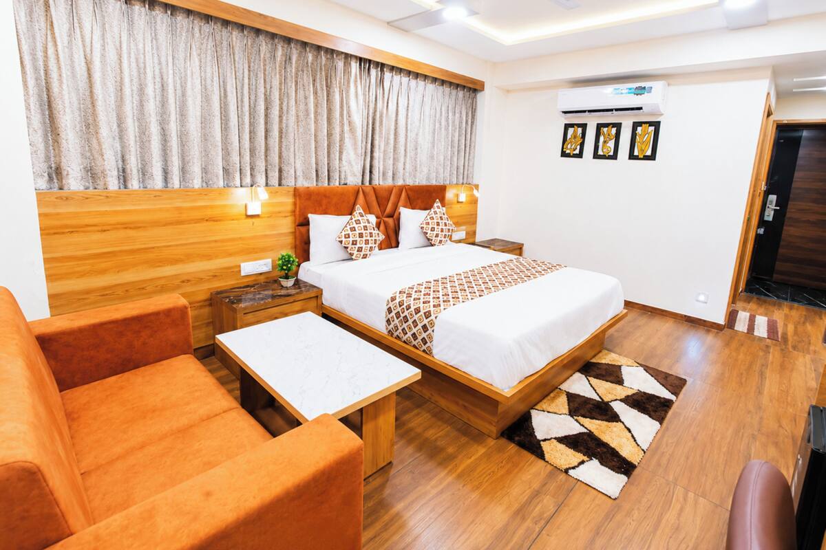 A hotel room with a bed, a desk, a chair, a nightstand, and a ceiling fan.