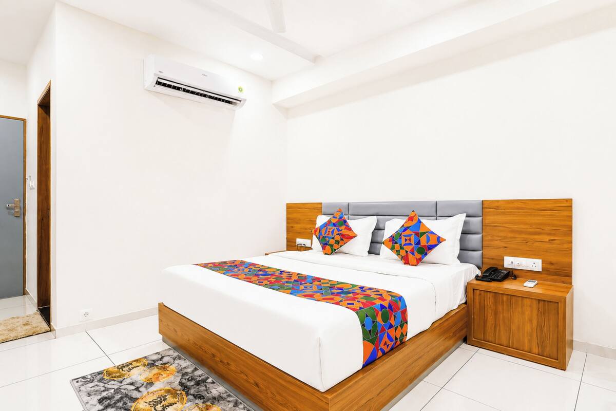 A modern bedroom with a wooden bed frame, white bedding, and colorful pillows.