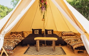 A tent with two beds, a central table, and a patterned rug.