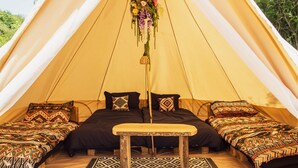 Una tenda con due letti, una panca e un addobbo appeso.