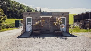 Un edificio rustico con una porta che reca l'indicazione 'Lodges' e 'Campsites', circondato da ghiaia e piante in vaso.