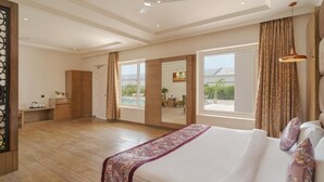 A spacious bedroom with a large bed, a ceiling fan, and a view of the outdoors. - Rudra Imperial Resort (Sitapur)