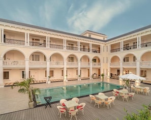 Hotel amb piscina central, múltiples balcons i zones d'estar a l'aire lliure.