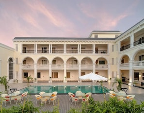 Hotel amb piscina, zones d'estar a l'exterior i edifici de diversos pisos amb balcons.
