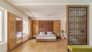 A bedroom with a large bed, a wooden headboard, a decorative screen, and a bench. - Rudra Imperial Resort (Sitapur)