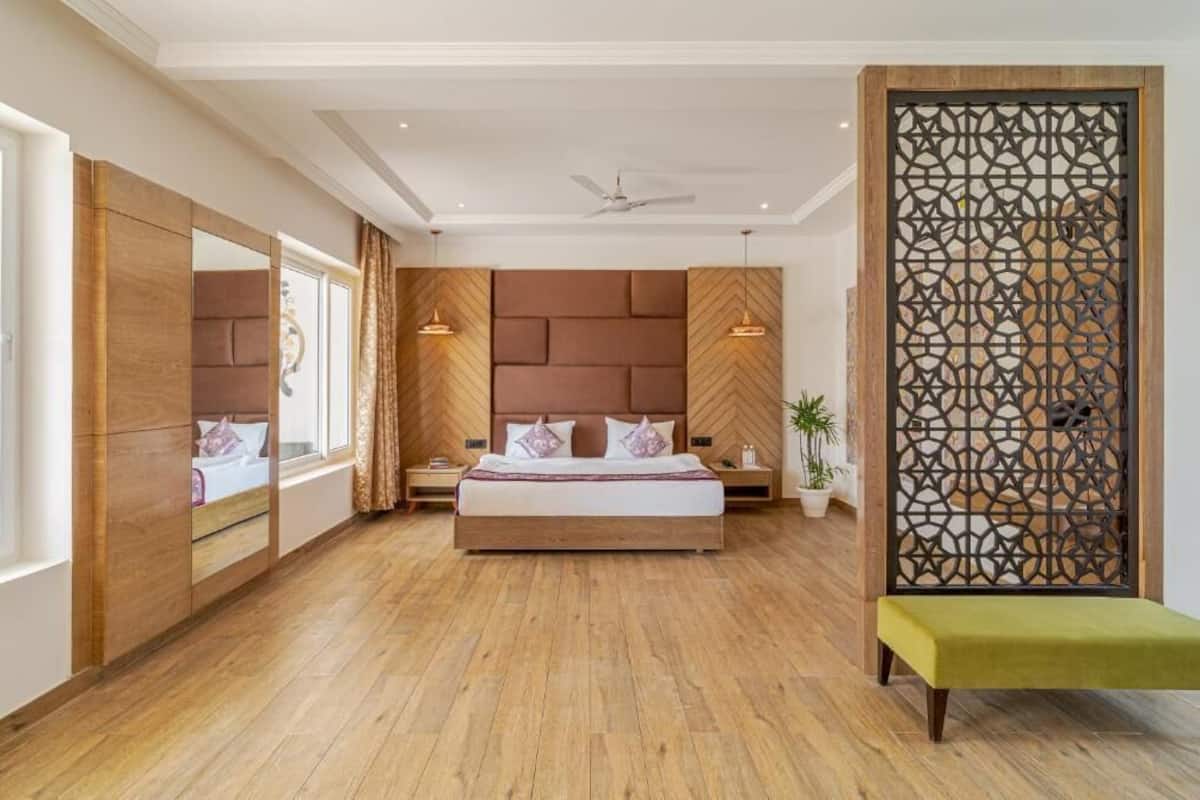 A bedroom with a large bed, a wooden headboard, a decorative screen, and a bench.