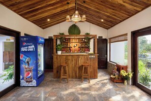 A bar area with a wooden ceiling, a Pepsi refrigerator, and a variety of bottles. - Laco green Trang An (Tay Hoa Lu)