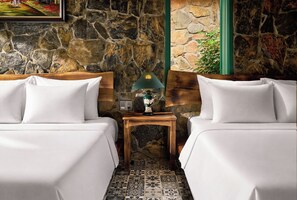 A hotel room with two beds, a nightstand with a lamp, and a stone wall. - Laco green Trang An (Tay Hoa Lu)