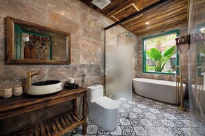 A bathroom with a stone wall, a wooden vanity, a sink, a toilet, and a bathtub. - Laco green Trang An (Tay Hoa Lu)
