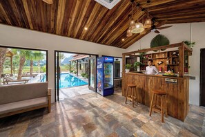 A bar area with a wooden counter, stools, and a Pepsi refrigerator. There is a pool visible through an open door. - Laco green Trang An (Tay Hoa Lu)