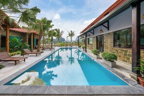 A rectangular swimming pool with clear blue water, surrounded by lounge chairs and potted plants. - Laco green Trang An (Tay Hoa Lu)