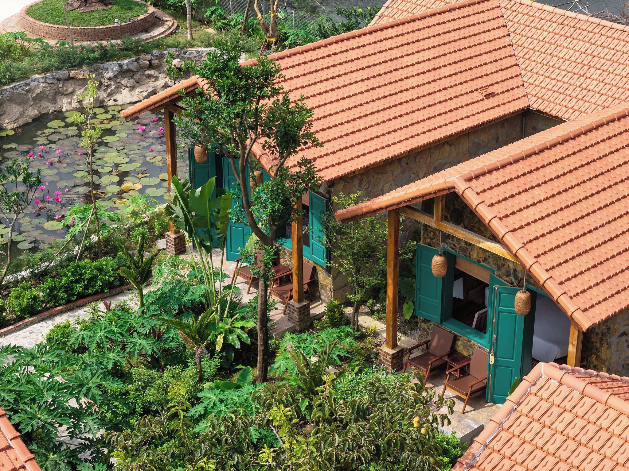 A traditional building with a tiled roof, surrounded by lush greenery and a pond with lotus flowers.