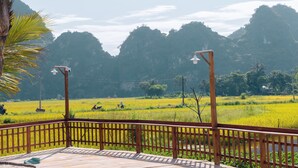 A wooden deck with a view of a rice field and mountains. - Laco green Trang An (Tay Hoa Lu)