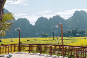 A wooden deck with a view of a rice field and mountains. - Laco green Trang An (Hoa Lu)