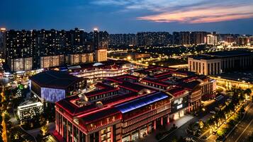 A high-rise building complex with multiple floors, surrounded by a well-lit urban area at dusk.