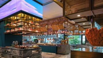 Un intérieur moderne comprenant un espace cuisine, des plans de travail en marbre et un grand écran numérique.