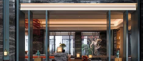 A spacious lobby with a marble floor, large windows, and modern furnishings.
