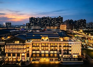 A modern hotel with multiple floors, large windows, and a well-lit facade.
