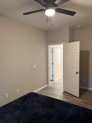 A room with a ceiling fan, a door leading to another room, and a light fixture.