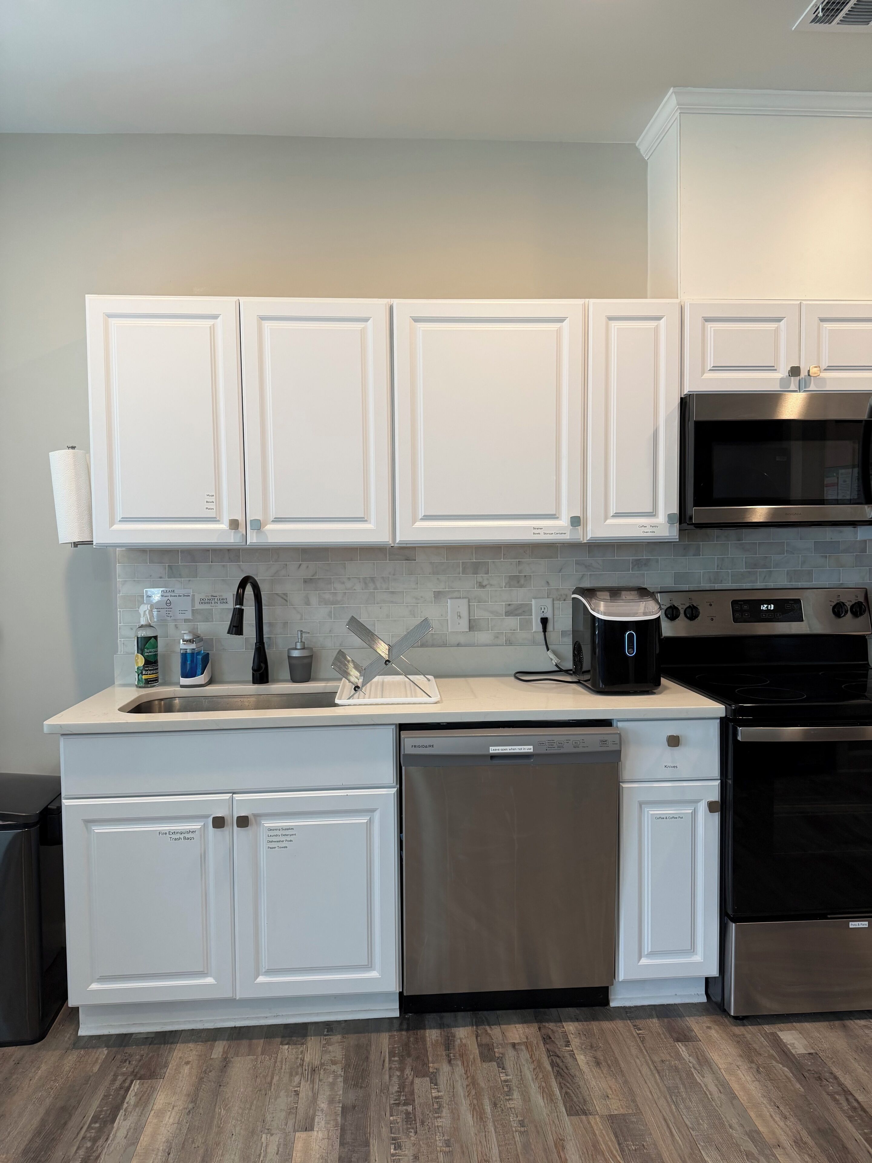 Una cocina moderna con armarios blancos, electrodomésticos de acero inoxidable y salpicadero de azulejos.