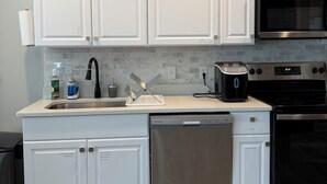 Una cocina moderna con armarios blancos, electrodomésticos de acero inoxidable y salpicadero de azulejos.