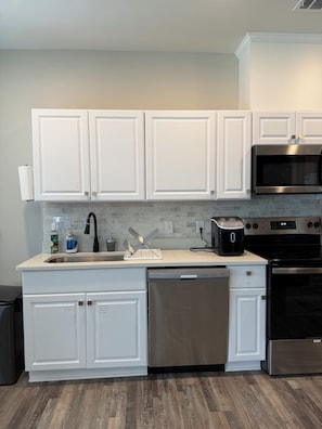 Una cocina moderna con armarios blancos, electrodomésticos de acero inoxidable y salpicadero de azulejos.