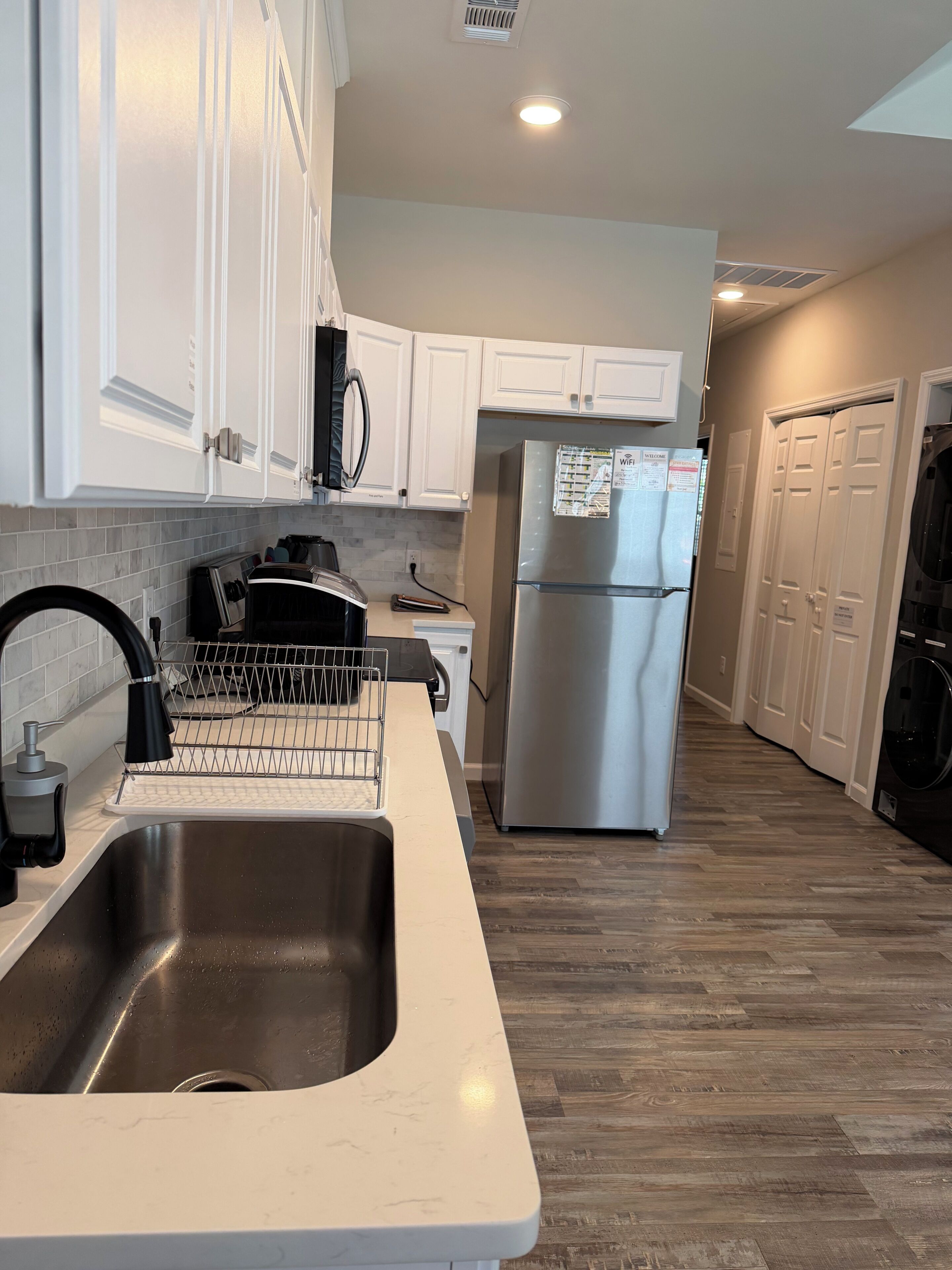 A modern kitchen with white cabinetry, a stainless steel refrigerator, and a dishwasher.