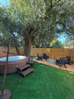 A backyard with a hot tub, outdoor furniture, and a wooden fence. - Close to downtown, HotTub, Fire Pit, Full Kitchen (Savannah)