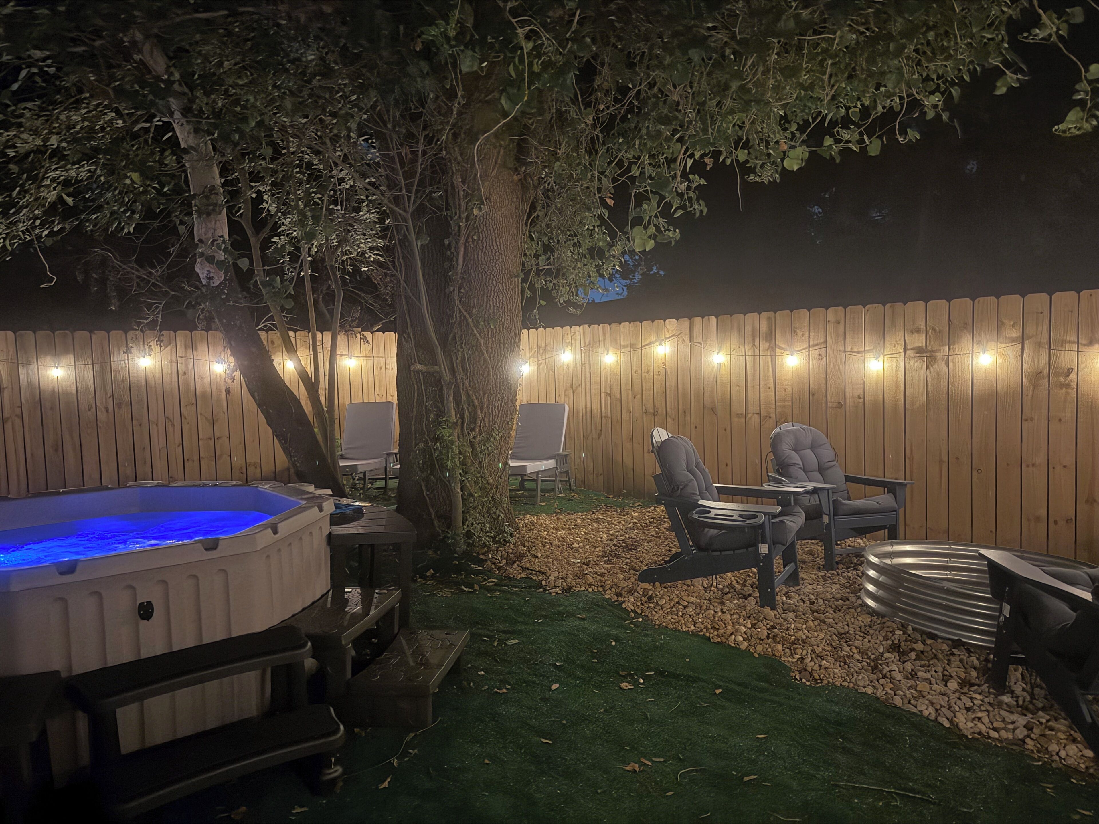 Un patio trasero con jacuzzi, zona de estar y valla de madera.