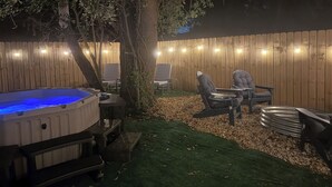 Un patio trasero con jacuzzi, zona de estar y valla de madera.