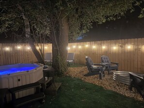 Un patio trasero con jacuzzi, zona de estar y valla de madera.