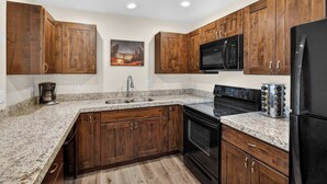 Une cuisine avec des meubles de rangement en bois, un four à micro-ondes, une cuisinière et un réfrigérateur.