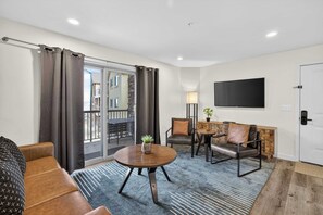 Ein modernes Wohnzimmer mit einer Couch, einem runden Couchtisch und einem an der Wand befestigten Fernseher.