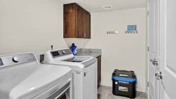 Une buanderie équipée d’un lave-linge, d’un sèche-linge, d’un meuble en bois et d’une poubelle.