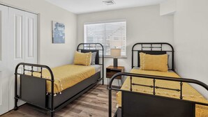 A bedroom with two beds, a bedside table, a lamp, a window with blinds, and a door. - 4-C Canyonlands Redcliff Condo (Pool View) (Moab)